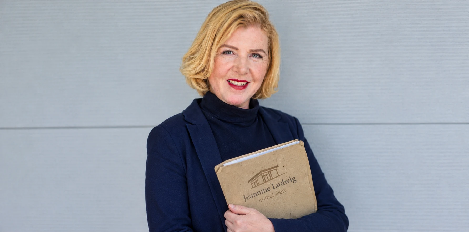 Jeannine Ludwig mit einer Mappe von Jeannine Ludwig Immobilien